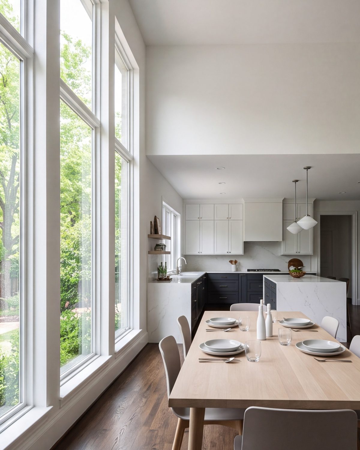 Bright dining area beside a new kitchen with tall windows and a long table